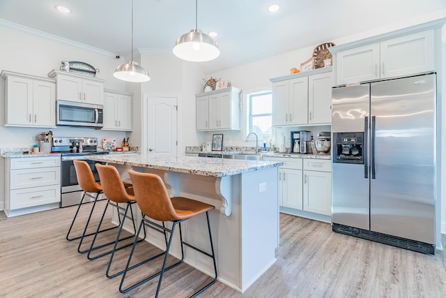 kitchen with a breakfast bar, crown molding, light wood-style flooring, appliances with stainless steel finishes, and a kitchen island