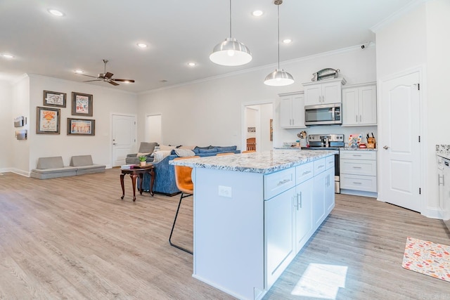 kitchen with a breakfast bar area, open floor plan, appliances with stainless steel finishes, a center island, and light wood finished floors