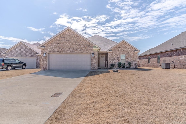 single story home with brick siding, a shingled roof, an attached garage, central AC, and driveway