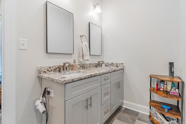 bathroom with a sink, baseboards, and double vanity