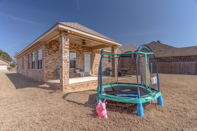 view of jungle gym with a patio area, a trampoline, fence, and a ceiling fan