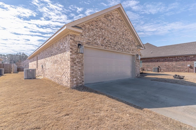 view of side of property featuring driveway, fence, cooling unit, and brick siding