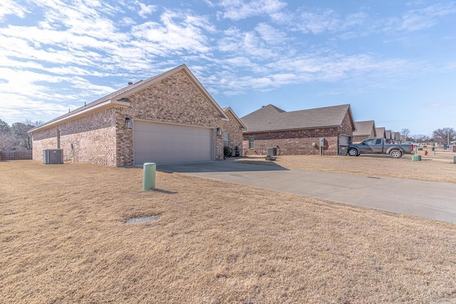 view of front of property with brick siding, an attached garage, cooling unit, driveway, and a front lawn