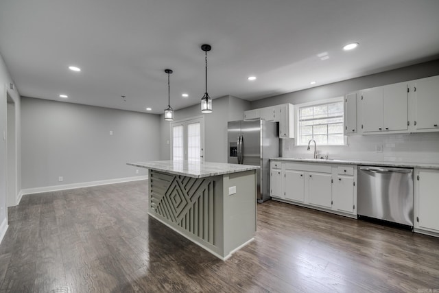 kitchen featuring appliances with stainless steel finishes, dark wood-type flooring, a sink, and a center island