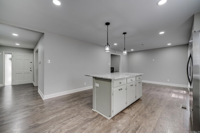 kitchen with recessed lighting, freestanding refrigerator, white cabinetry, a kitchen island, and wood finished floors