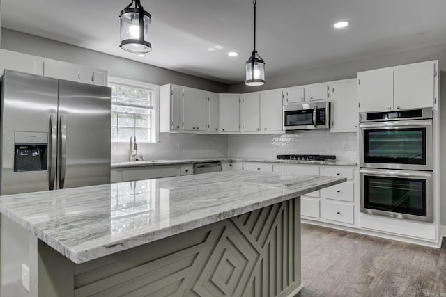 kitchen with light stone countertops, appliances with stainless steel finishes, decorative backsplash, and light wood-style floors