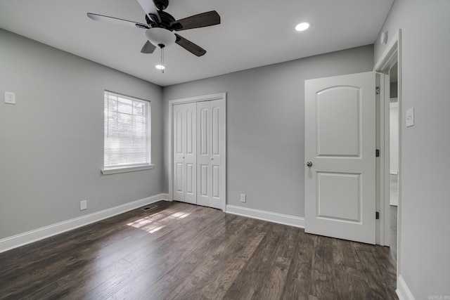 unfurnished bedroom with a closet, visible vents, ceiling fan, wood finished floors, and baseboards