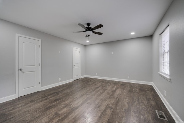 unfurnished room with baseboards, ceiling fan, visible vents, and dark wood-type flooring