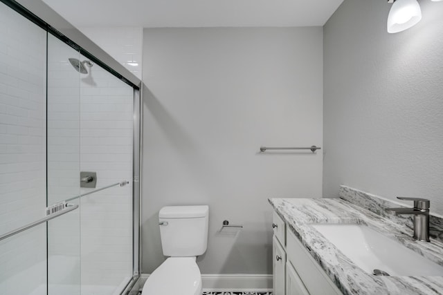 full bathroom featuring toilet, a stall shower, baseboards, and vanity