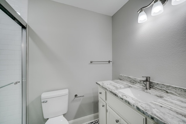 bathroom with baseboards, vanity, toilet, and an enclosed shower