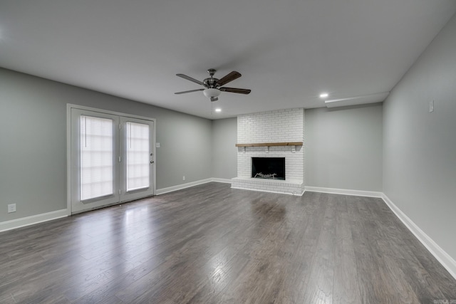 unfurnished living room featuring dark wood-style floors, a fireplace, baseboards, and ceiling fan