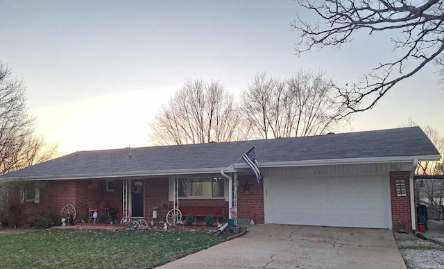 ranch-style house with a garage, a yard, driveway, and brick siding