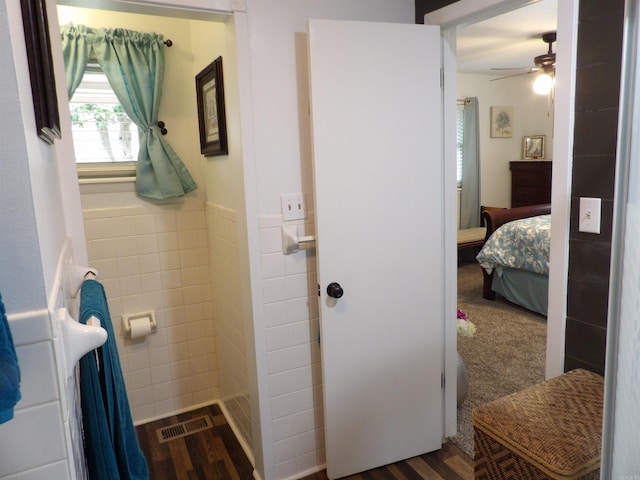 ensuite bathroom featuring tile walls, visible vents, ensuite bathroom, wainscoting, and wood finished floors