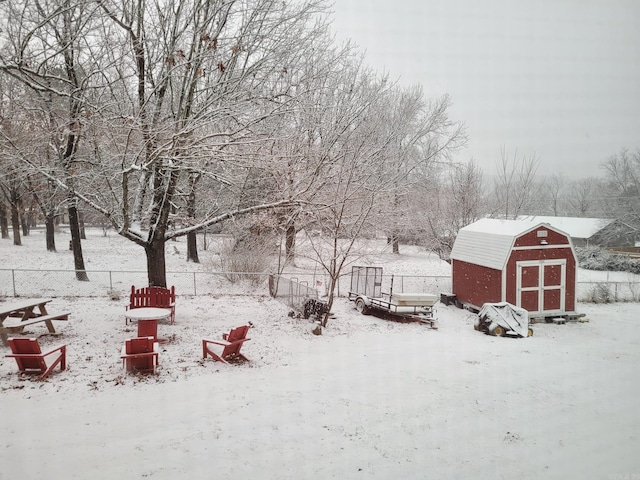 yard covered in snow with a storage shed, an outbuilding, and a fenced backyard