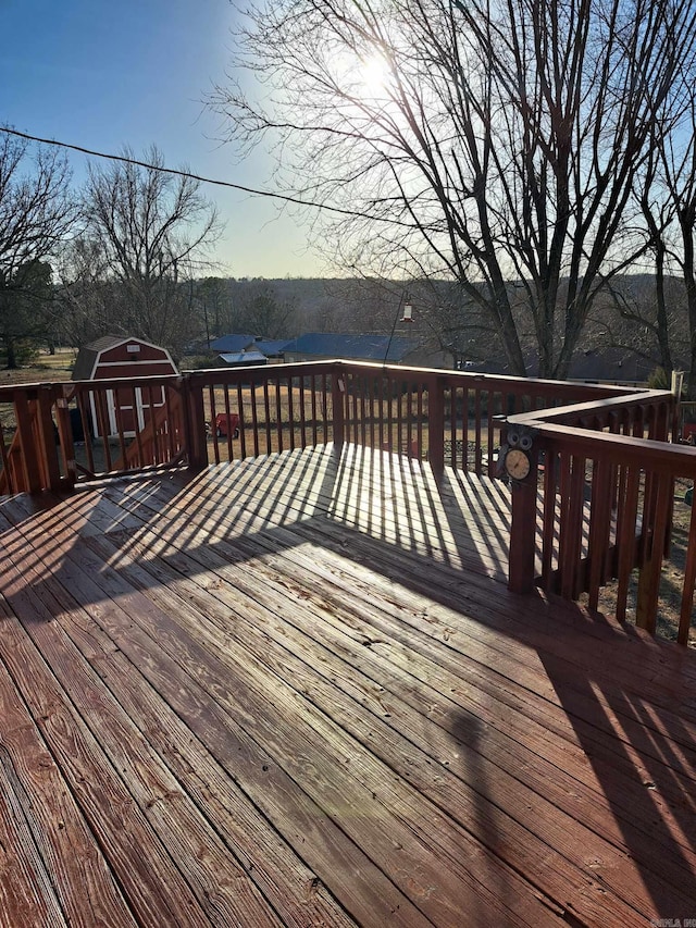 wooden terrace featuring a storage unit and an outbuilding