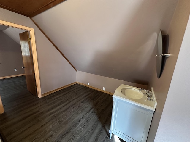 bathroom featuring vanity, baseboards, vaulted ceiling, and wood finished floors