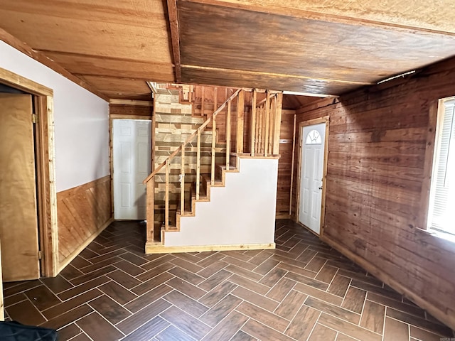 below grade area featuring stairs, wood walls, and a wainscoted wall