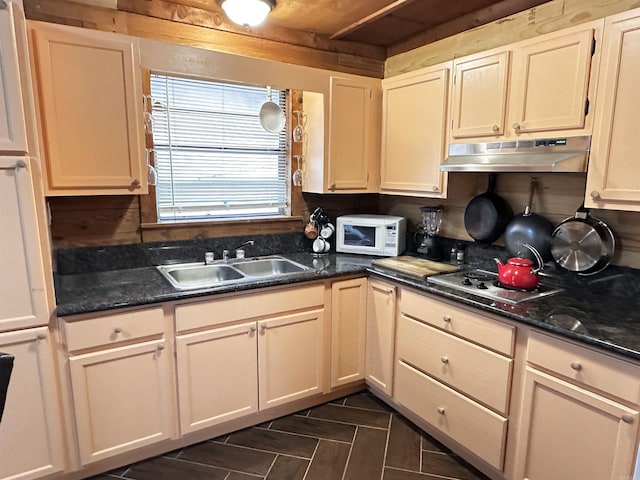 kitchen with a sink, white microwave, under cabinet range hood, and stainless steel cooktop