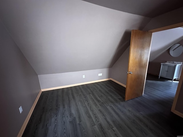 bonus room with baseboards, lofted ceiling, a sink, and dark wood-type flooring