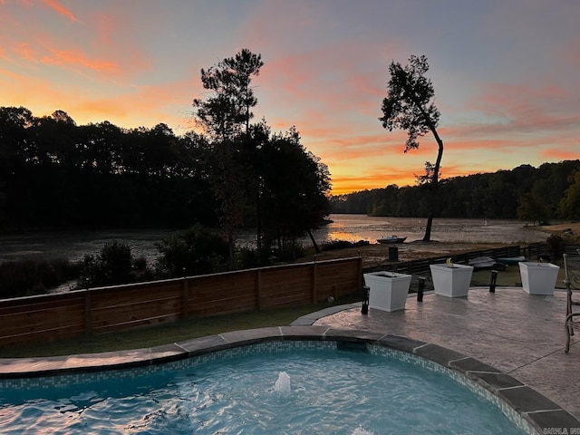 pool at dusk featuring fence and a patio