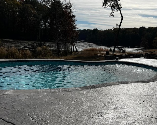 outdoor pool featuring a patio and a wooded view