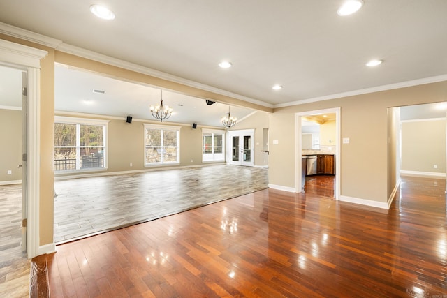 unfurnished living room featuring visible vents, an inviting chandelier, ornamental molding, wood finished floors, and baseboards