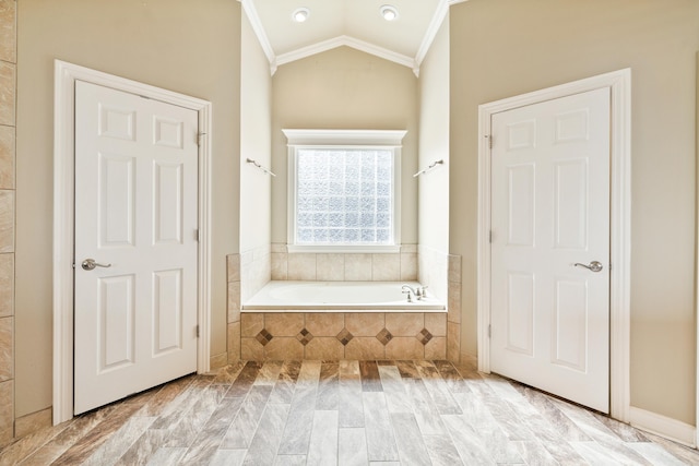 bathroom featuring ornamental molding, vaulted ceiling, and a bath