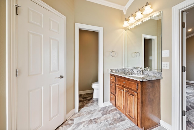 bathroom with baseboards, crown molding, vanity, and toilet