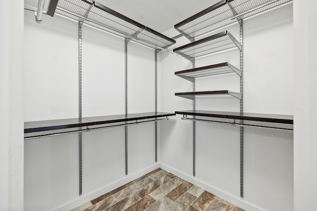 spacious closet featuring stone finish floor