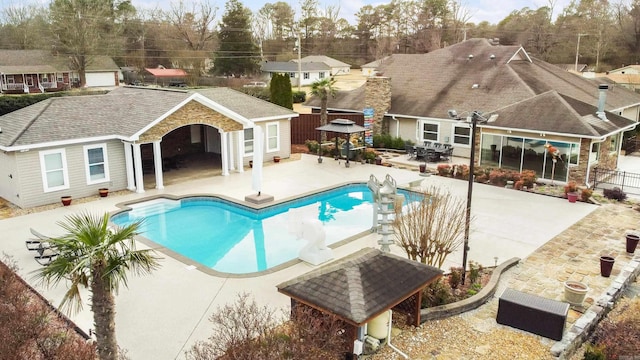 outdoor pool featuring an outbuilding, a gazebo, a patio area, and fence