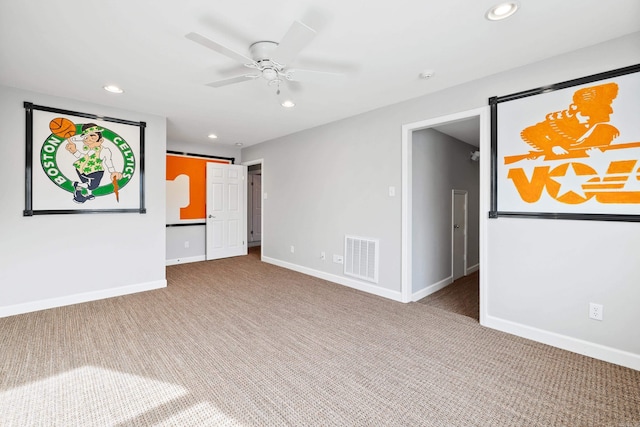 carpeted empty room with a barn door, visible vents, baseboards, and recessed lighting