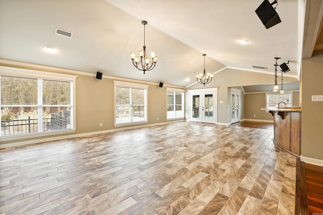 unfurnished living room featuring lofted ceiling, visible vents, a notable chandelier, and french doors