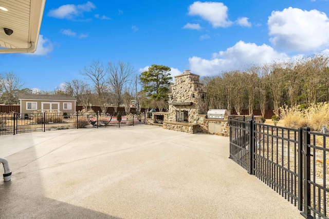 view of patio with a grill, fence, an outbuilding, and an outdoor stone fireplace