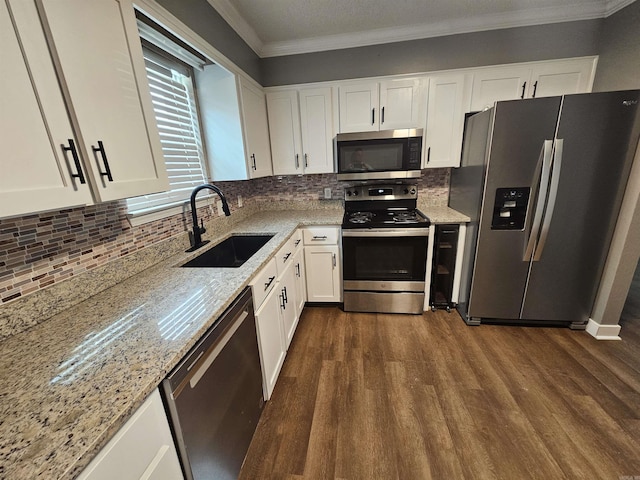 kitchen featuring stainless steel appliances, a sink, white cabinetry, ornamental molding, and light stone countertops