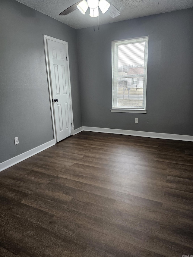 spare room with dark wood-style floors, a textured ceiling, a ceiling fan, and baseboards