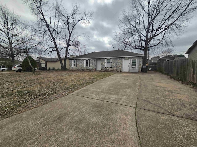 view of front of house featuring stone siding, fence, and concrete driveway