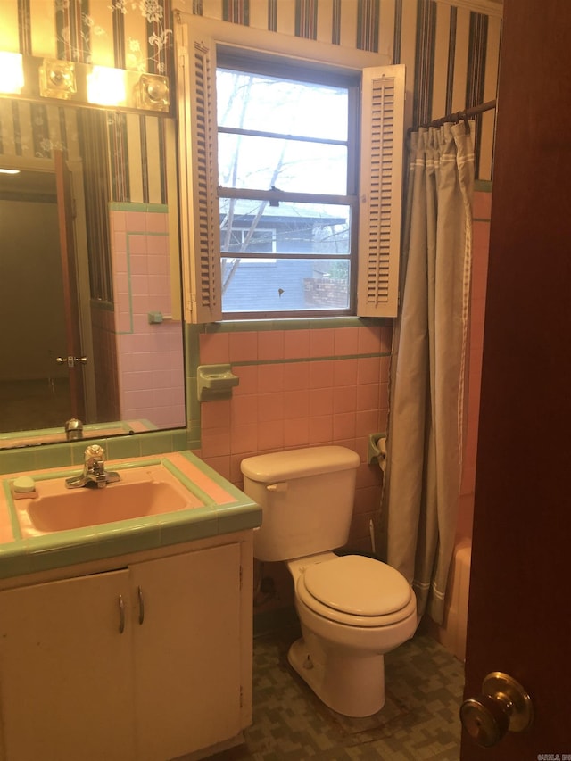 full bath featuring tile walls, vanity, toilet, and wallpapered walls