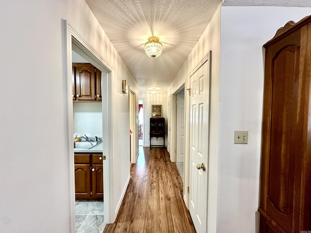 312 State St, Dardanelle, AR 72834 - hall featuring a sink, a textured ceiling, baseboards, and wood finished floors