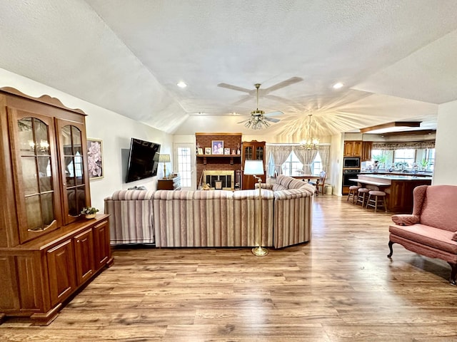 312 State St, Dardanelle, AR 72834 - living area with vaulted ceiling, light wood finished floors, a textured ceiling, and ceiling fan with notable chandelier