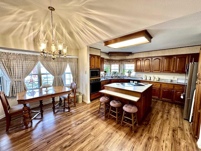 312 State St, Dardanelle, AR 72834 - kitchen featuring a textured ceiling, dark wood-type flooring, a kitchen breakfast bar, appliances with stainless steel finishes, and a center island