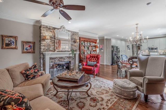 living room featuring recessed lighting, ceiling fan with notable chandelier, a fireplace, wood finished floors, and ornamental molding