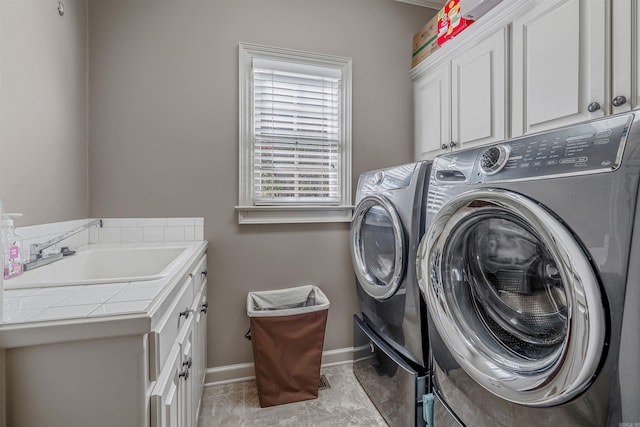 laundry room with baseboards, cabinet space, independent washer and dryer, and a sink