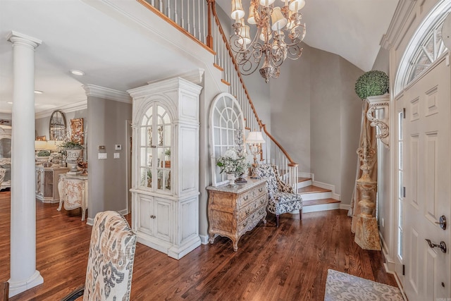 foyer entrance with dark wood-style floors, stairway, decorative columns, and an inviting chandelier