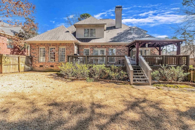 rear view of property with a deck, a gazebo, brick siding, and fence