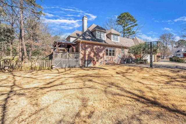 exterior space featuring brick siding, fence, and a chimney