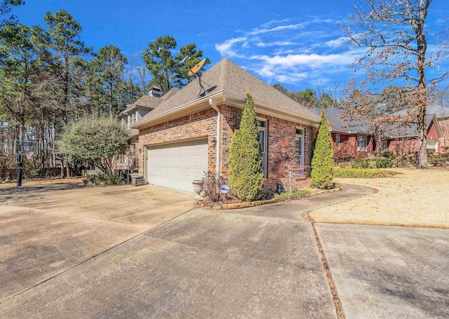 view of side of home featuring brick siding, roof with shingles, a chimney, an attached garage, and driveway