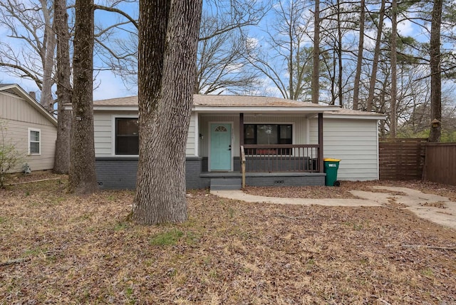 view of front of home with a porch, crawl space, brick siding, and fence