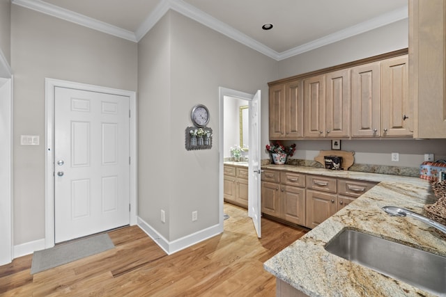 kitchen featuring a sink, baseboards, light stone countertops, light wood finished floors, and crown molding