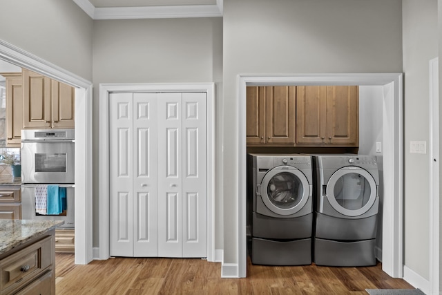 washroom featuring cabinet space, light wood finished floors, baseboards, crown molding, and washer and dryer