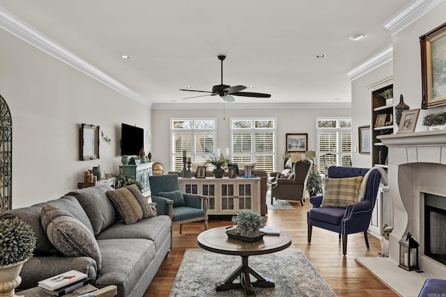 living area with a healthy amount of sunlight, crown molding, a fireplace, and wood finished floors